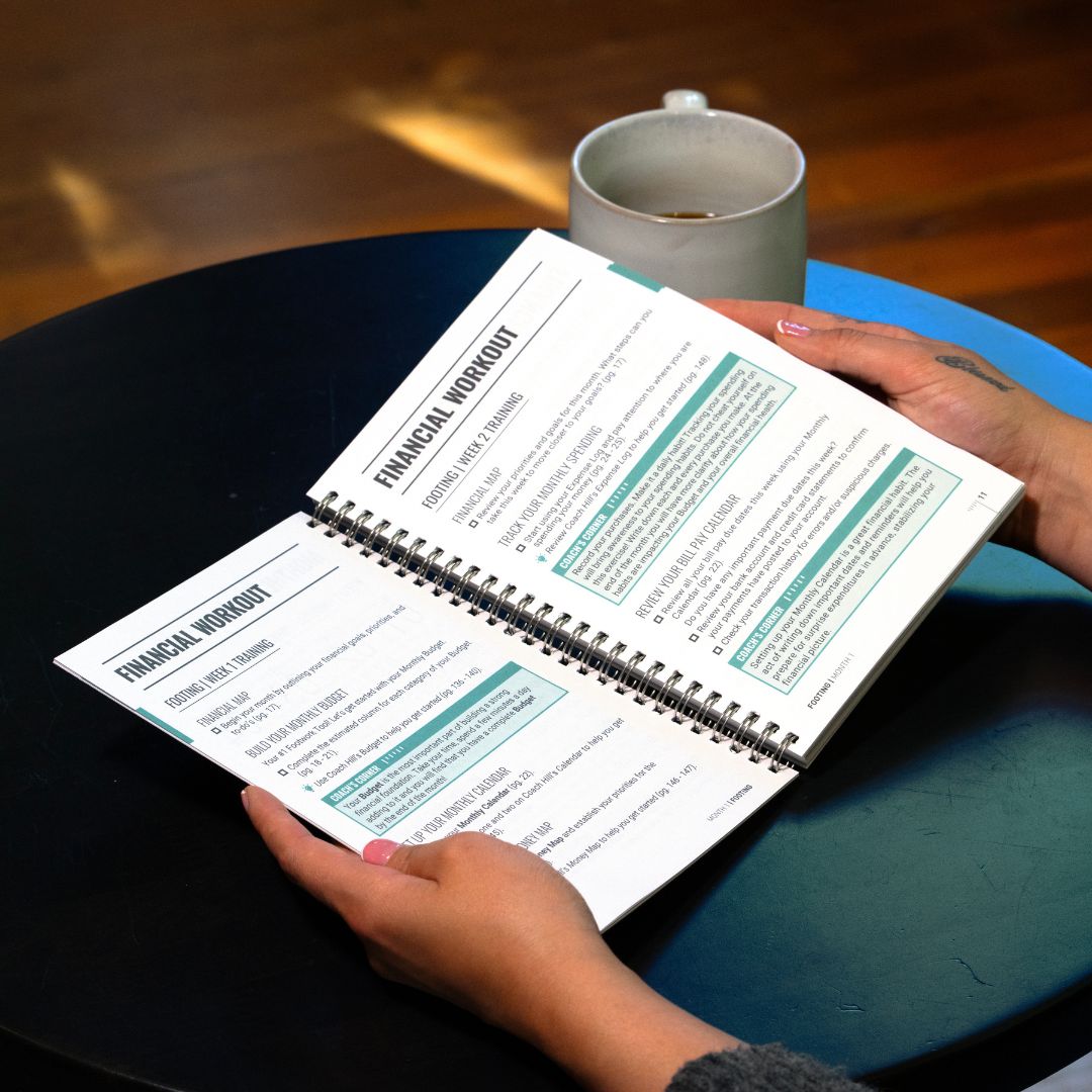 person using a physical financial planner to complete weekly money planning at a coffee shop
